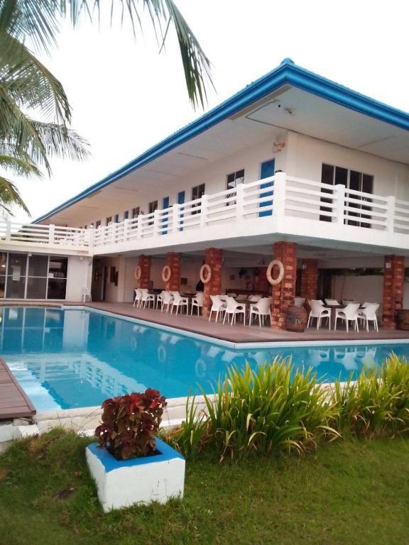 a hotel with a swimming pool in front of a building at Brizo Hotel and Beach Resort Bataan in Morong