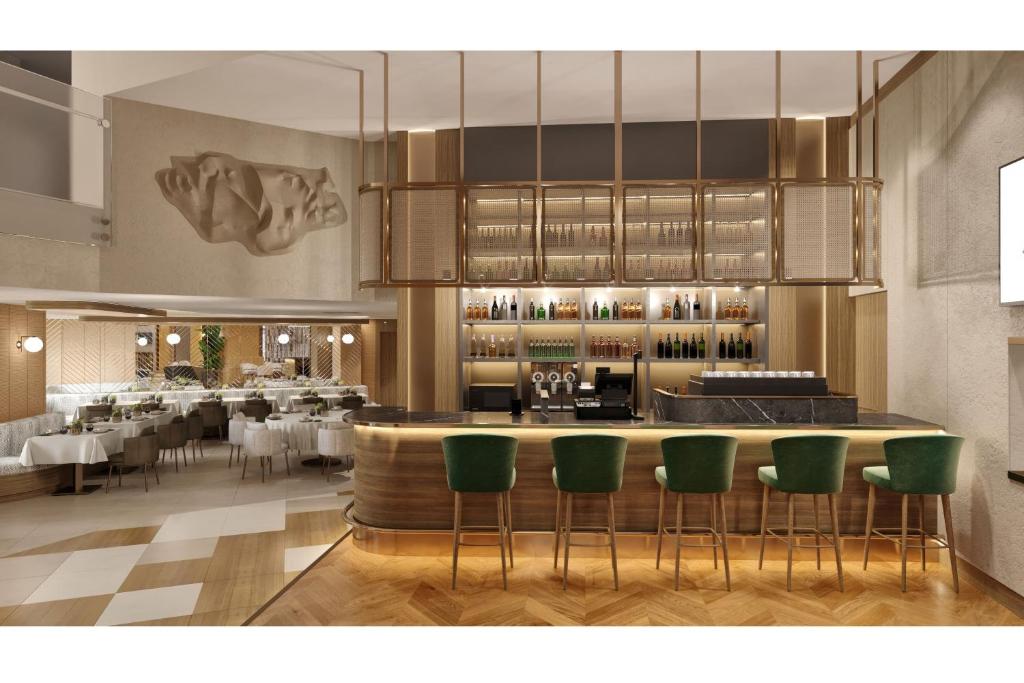 a restaurant with a bar with green chairs at Delta Hotels Istanbul West in Istanbul