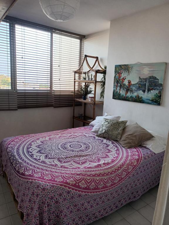 a bedroom with a large bed with a purple blanket at Las orquideas in Caraballeda