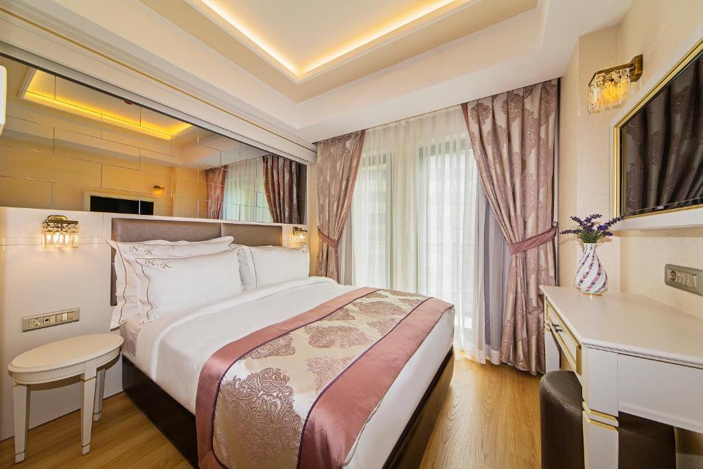 イスタンブールにあるグランド ナキ ホテルのベッドとデスクが備わるホテルルームです。