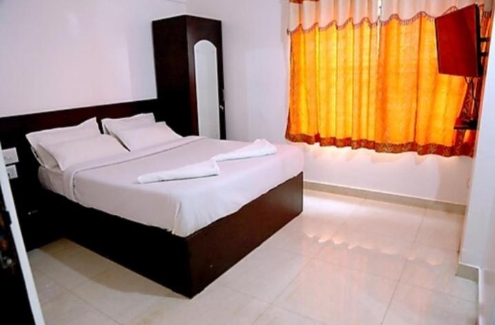 ein Schlafzimmer mit einem Bett und einem gelben Vorhang in der Unterkunft manjunatha residency in Chikmagalur