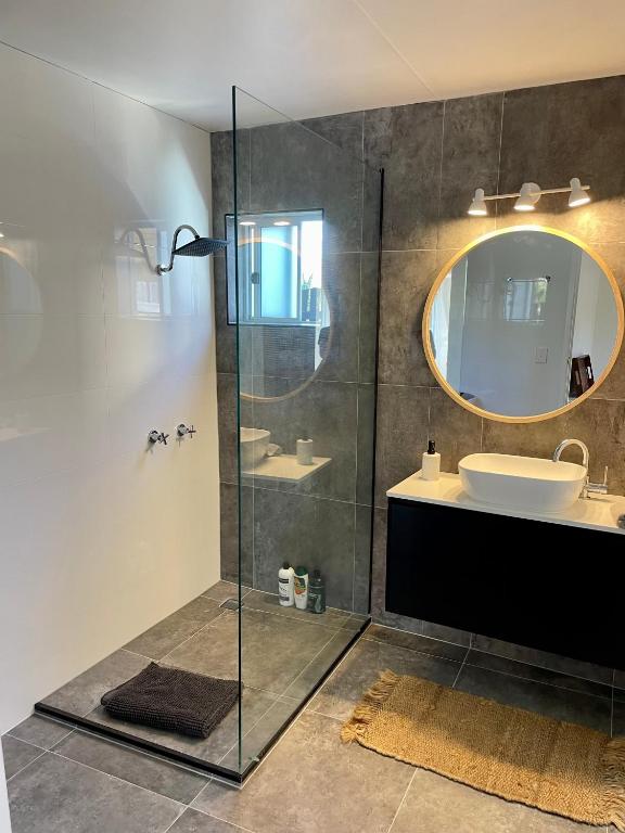 een badkamer met een douche, een wastafel en een spiegel bij The Art Gallery Boreen Point in Cootharaba