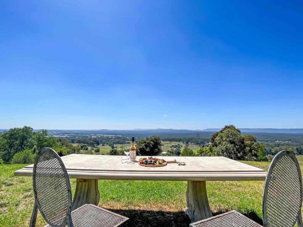 a picnic table with two chairs and a bottle of wine at Elouera Retreat in Mount View