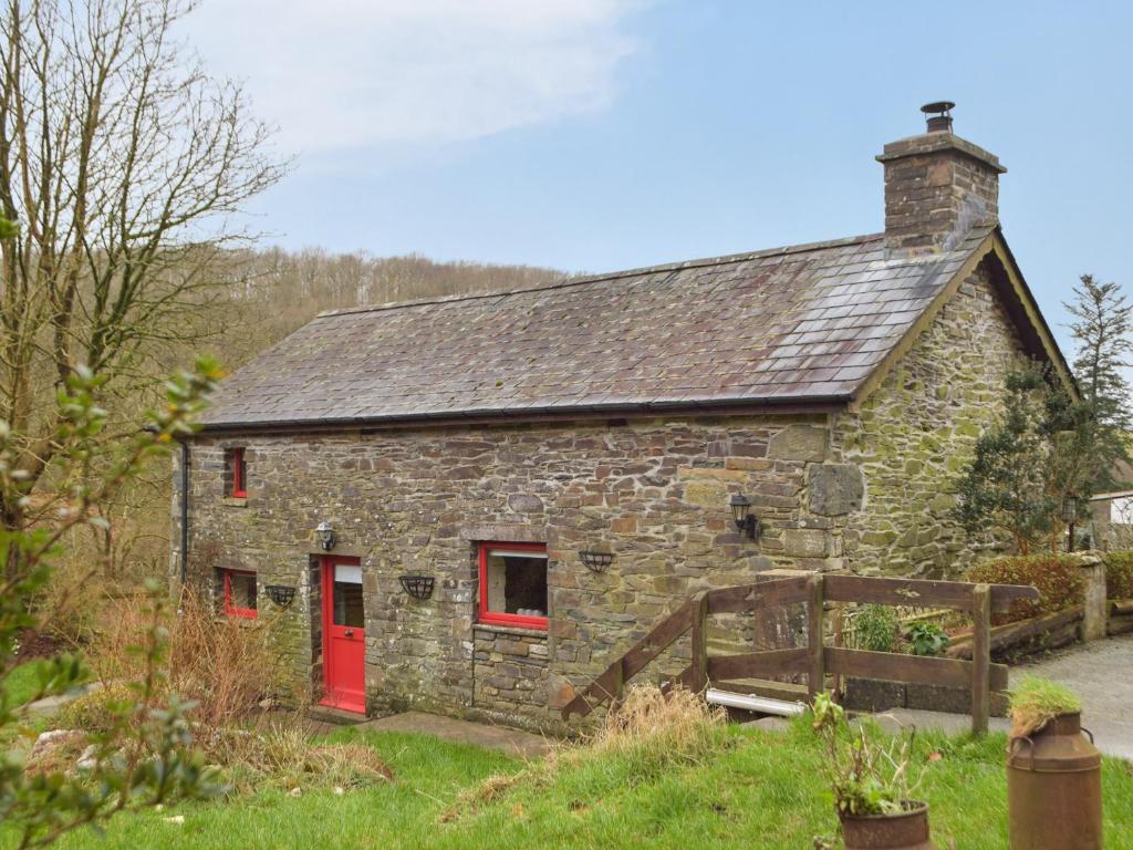 an old stone house with red doors and a fence at Ty Tarw - Uk46189 in Llanybyther