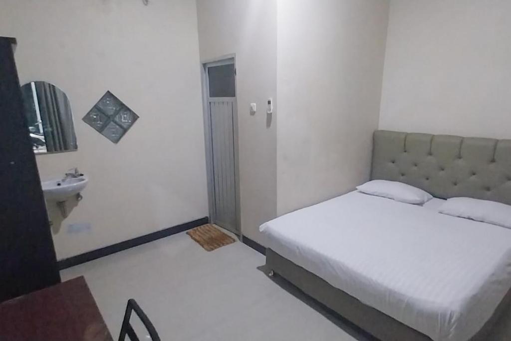 ein kleines Schlafzimmer mit einem Bett und einem Waschbecken in der Unterkunft Wisma Merdeka Syariah RedPartner in Palembang