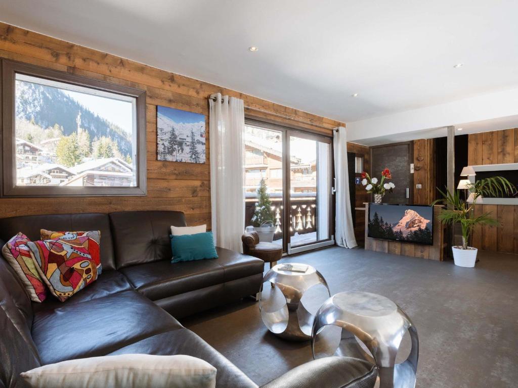 - un salon avec un canapé en cuir et une grande fenêtre dans l'établissement Duplex de Luxe au Cœur de La Clusaz, 6 Pers, 118m², Proche Pistes et Loisirs - FR-1-304-286, à La Clusaz
