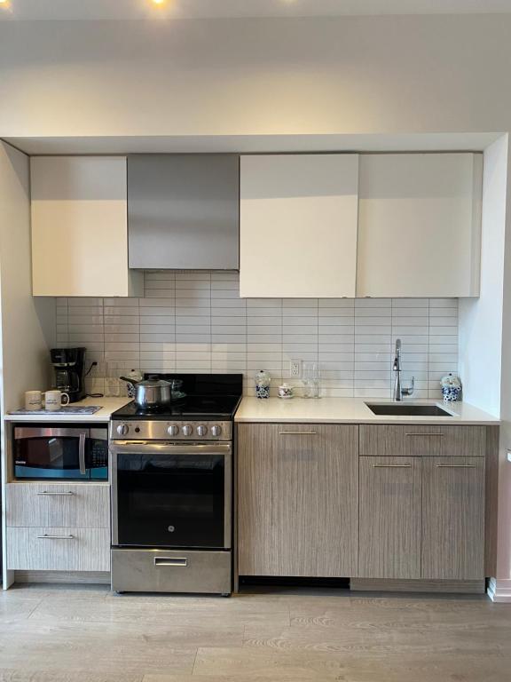 una cucina con elettrodomestici in acciaio inossidabile e armadietti bianchi di Cozy holiday home a Toronto
