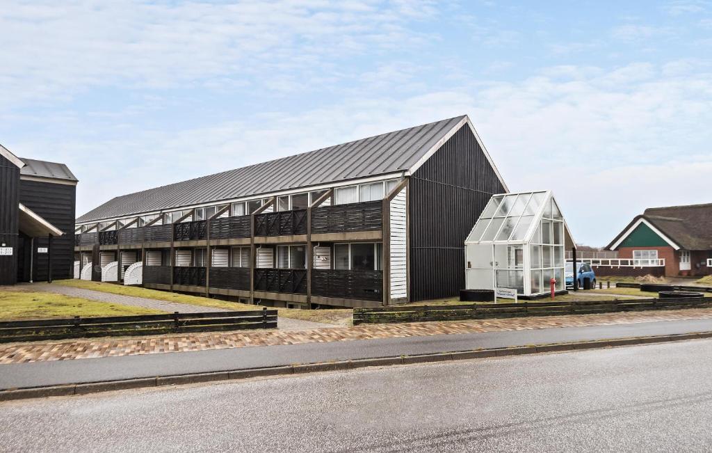 un gran edificio negro con una casa al lado de una calle en Beautiful Apartment In Fan With Kitchen, en Fanø