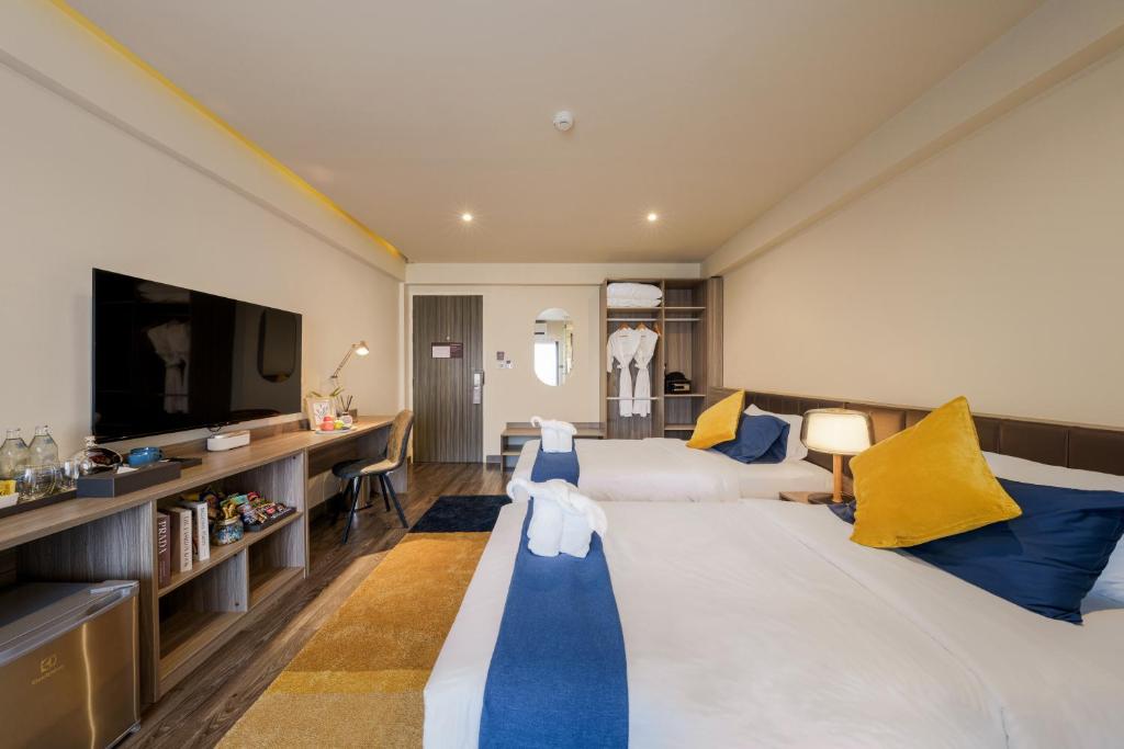 バンコクにあるEight Hotel Ariの大型ベッドとテレビが備わるホテルルームです。