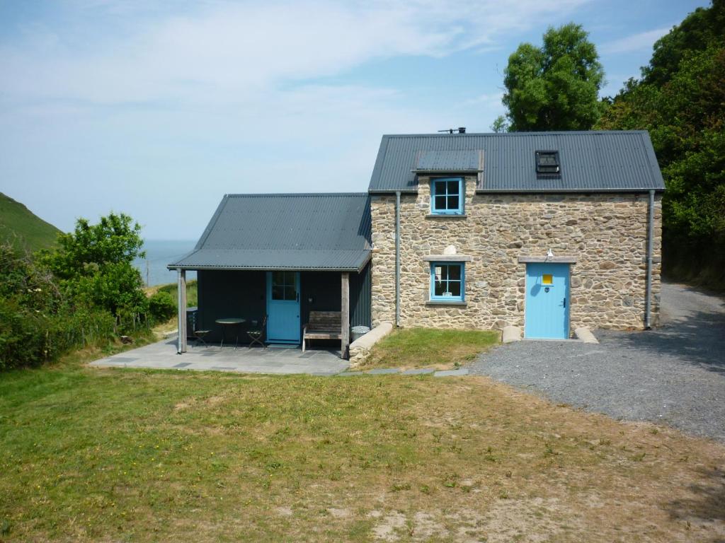 a stone house with a blue door in a field at Dolwylan Barn in Llandysul