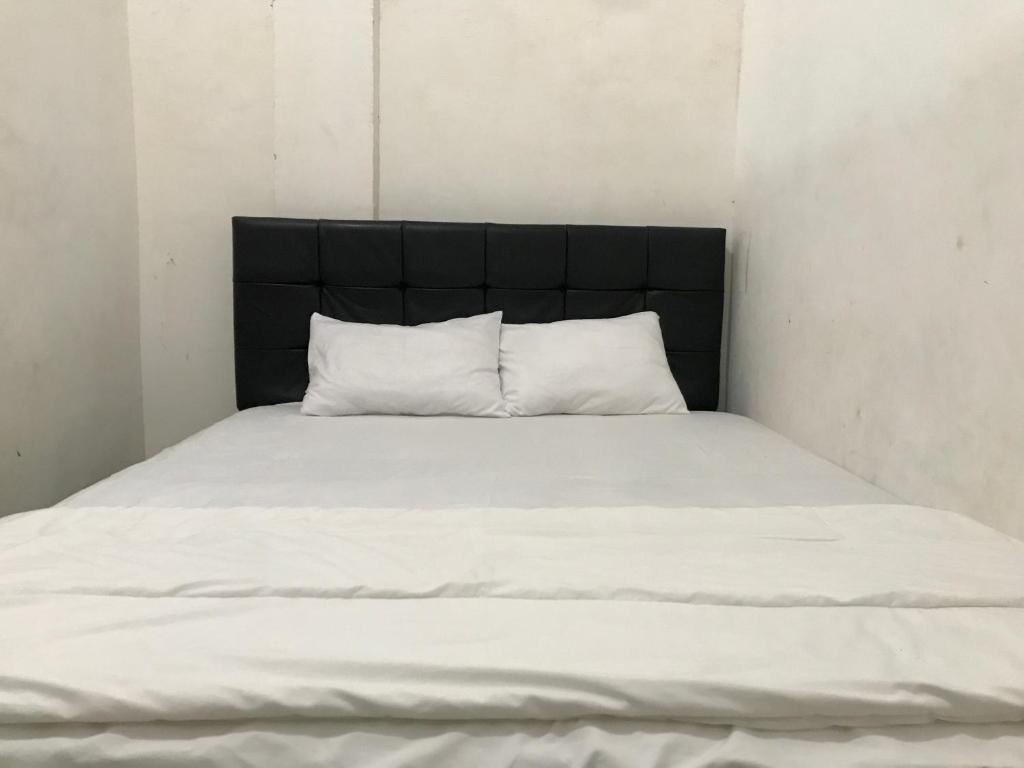a bed with white sheets and a black headboard at Grand Hagawa Syariah near Alun Alun Lamongan RedPartner in Lamongan