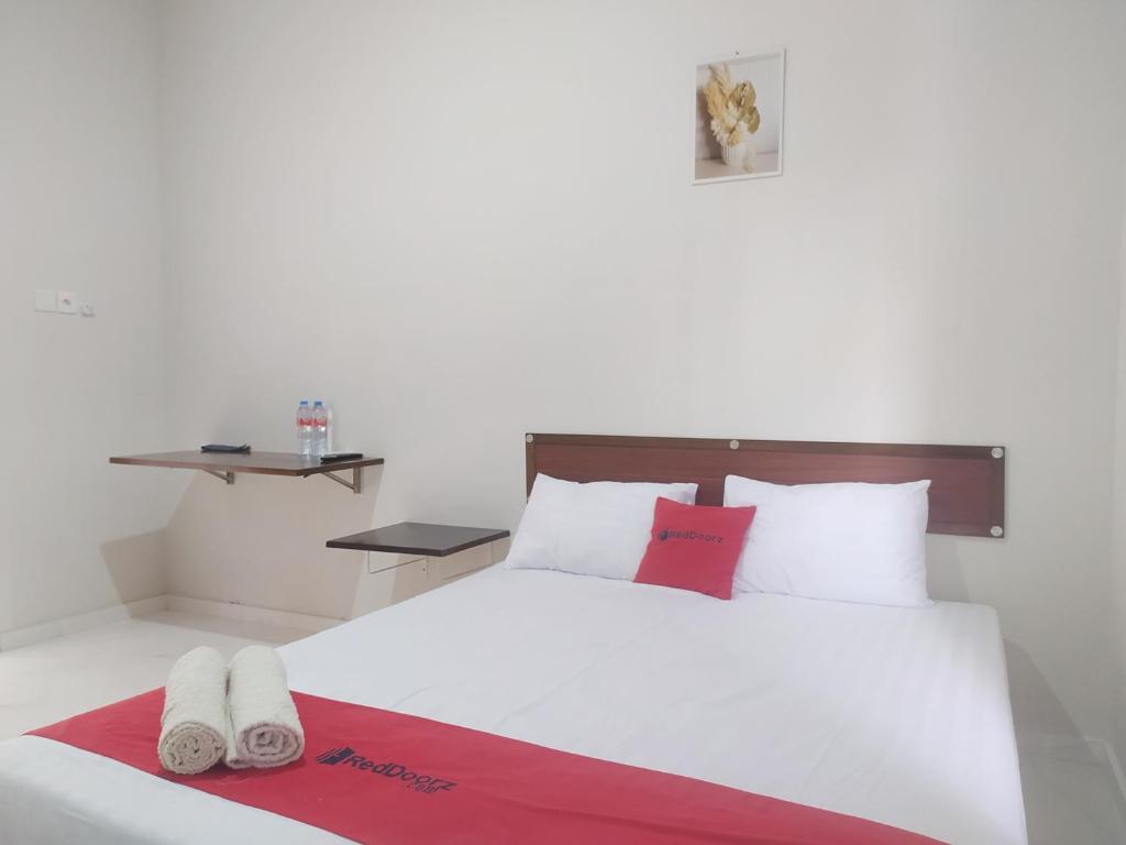 ein Schlafzimmer mit einem weißen Bett mit roten und weißen Kissen in der Unterkunft RedDoorz Syariah Near Stasiun Purwokerto in Purwokerto