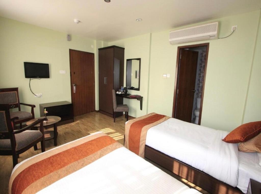 a hotel room with two beds and a chair at The Luxe Inn Boutique Hotel in Kathmandu