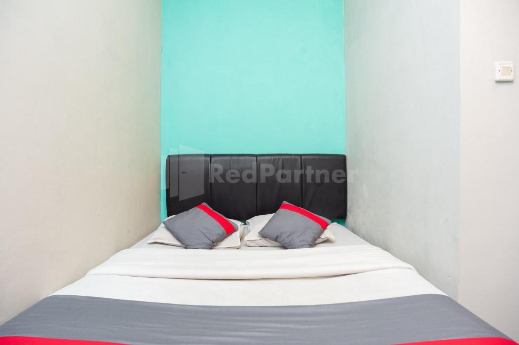 a bed in a room with two pillows on it at J&B Rooms Utan Kayu Jakarta Mitra RedDoorz in Jakarta