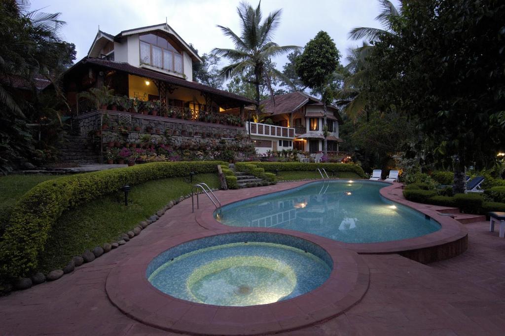 a house with a swimming pool in front of a house at Tranquil Resort - Blusalzz Collection, Wayanad - Kerala in Ambalavayal