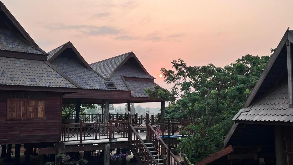 a wooden building with a deck and a house at อีสานบ้านเฮาฟาร์ม Esan Banhao Farm in Ban Om Ko