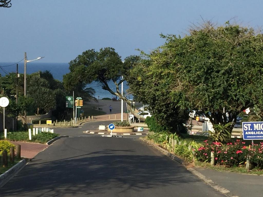 an empty road with trees and a street sign at Close to the sea - Upstairs Sea Facing En Suite Bedroom In Main House in Durban