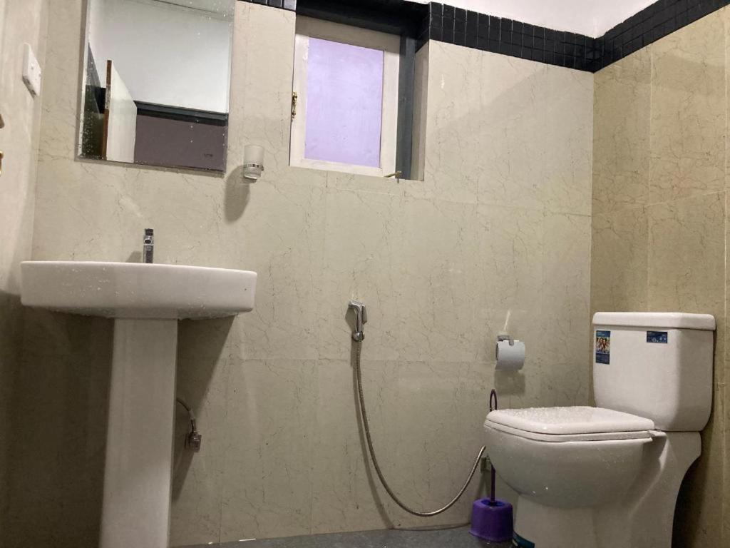 a bathroom with a toilet and a sink and a window at Mauji's Villa Hotel & Guest House in Prayagraj