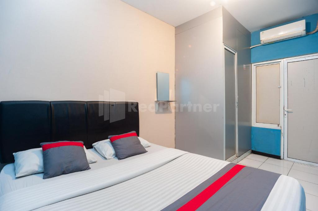 um quarto com uma cama grande com almofadas vermelhas e azuis em J&B Rooms Pramuka Jakarta Mitra RedDoorz em Jakarta