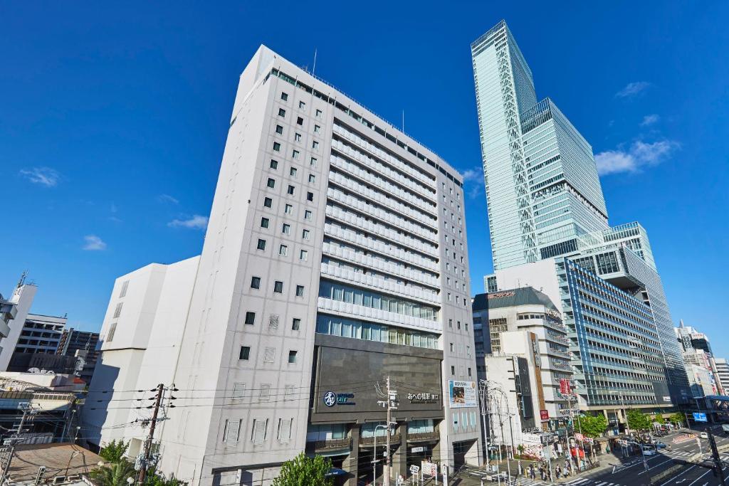 un grand bâtiment blanc dans une ville avec de grands bâtiments dans l'établissement Miyako City Osaka Tennoji, à Osaka