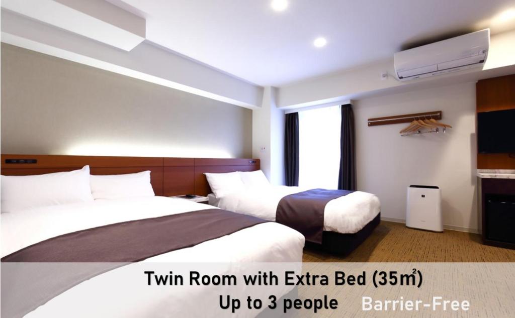 a hotel room with two beds and a tv at LUXCARE HOTEL in Osaka