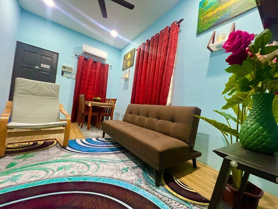 uma sala de estar com um sofá e cortinas vermelhas em HH Homestay Dungun em Kampong Gok Kapor