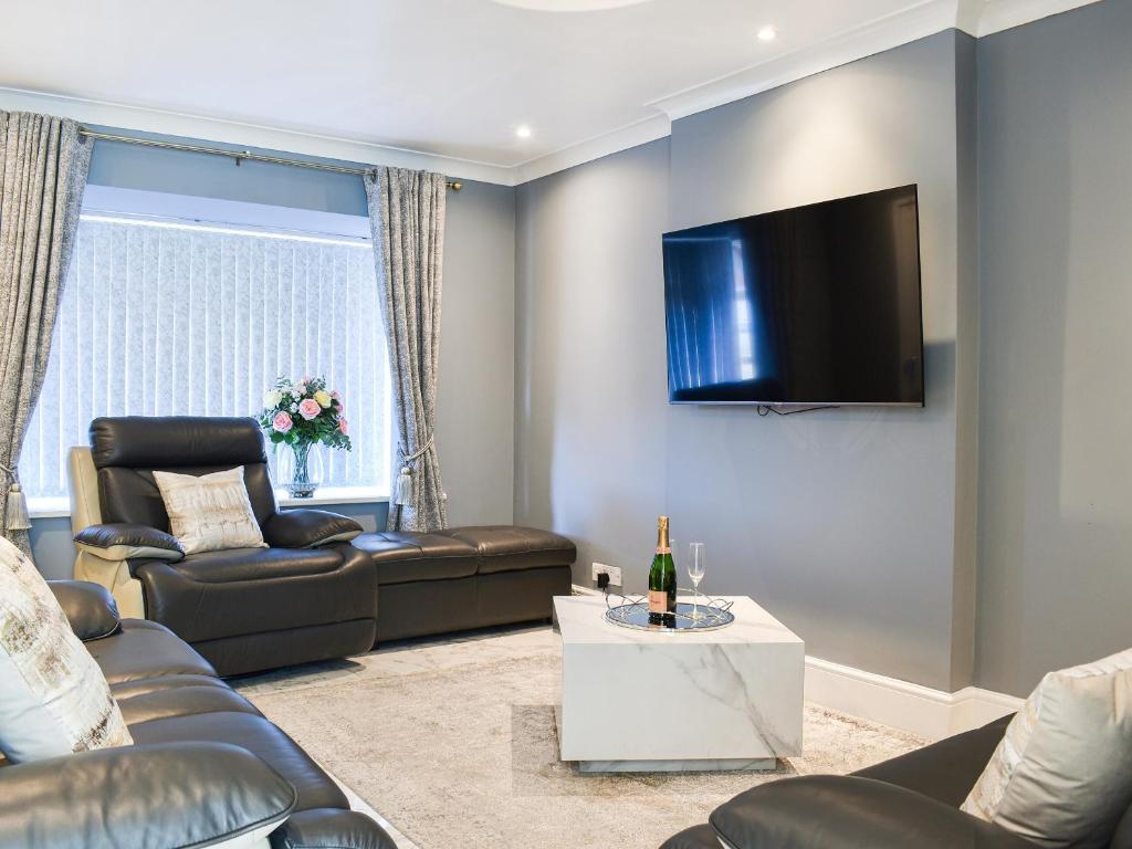 ein Wohnzimmer mit einem Sofa und einem TV an der Wand in der Unterkunft Badger Cottage in Thornaby on Tees