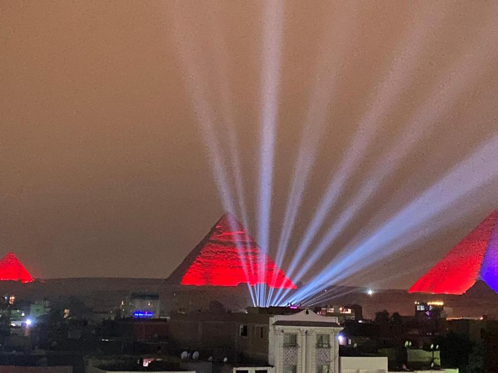 a view of the pyramids at night with red and blue lights at desert horus hotel in Cairo