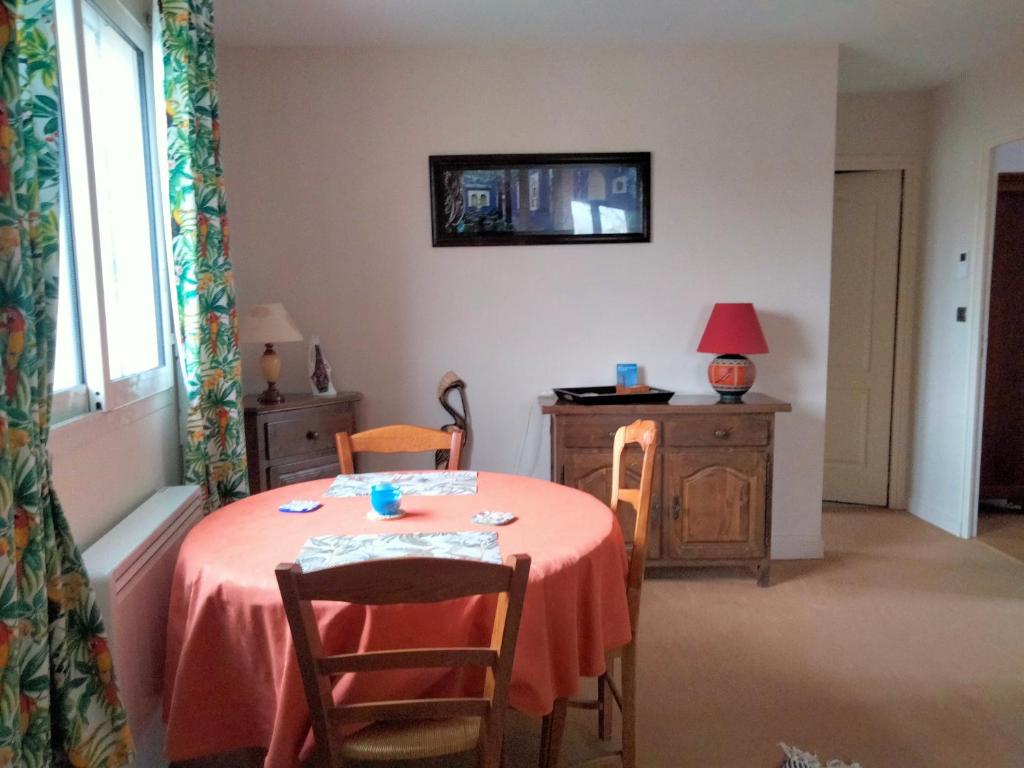 Habitación con mesa con sillas y TV en la pared. en Chambre à louer chez l'habitant en Payré