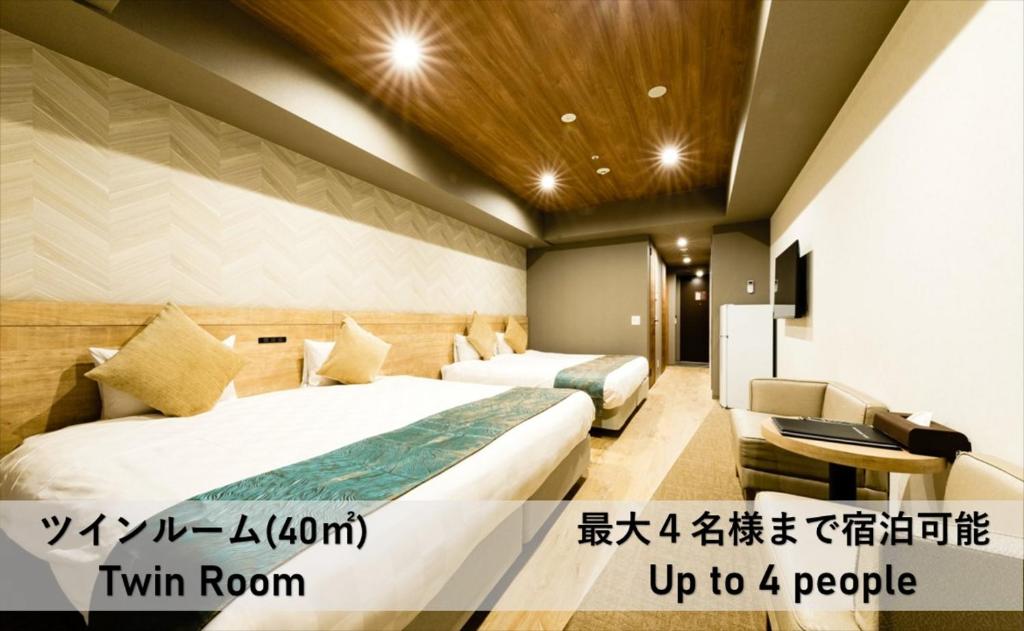大阪市にあるTAKUTO HOTEL 心斎橋のベッド2台とソファが備わるホテルルームです。