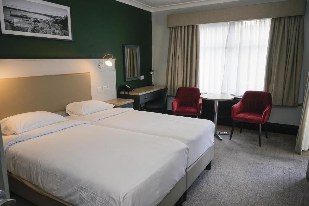 a hotel room with a bed and two red chairs at Park Inn by Radisson Bournemouth in Bournemouth