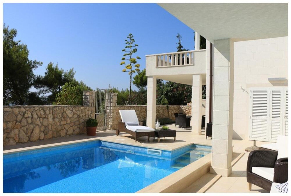 - une piscine avec 2 chaises et une maison dans l'établissement Apartments Fortunata, à Primošten