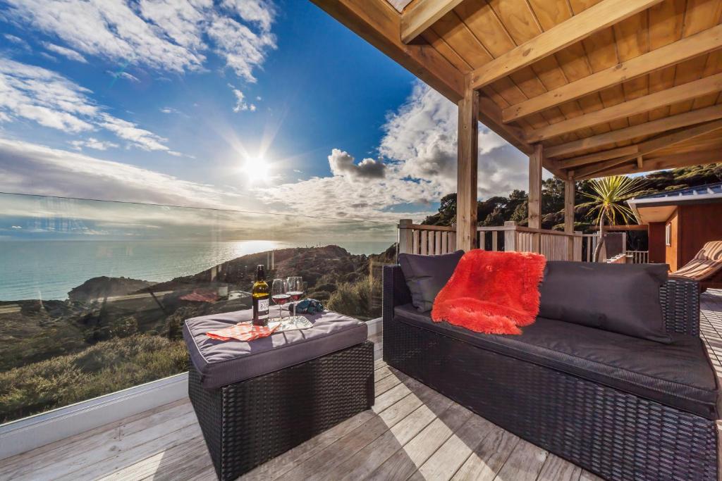 a patio with a couch and a table on a deck at Romantic Piha in Piha