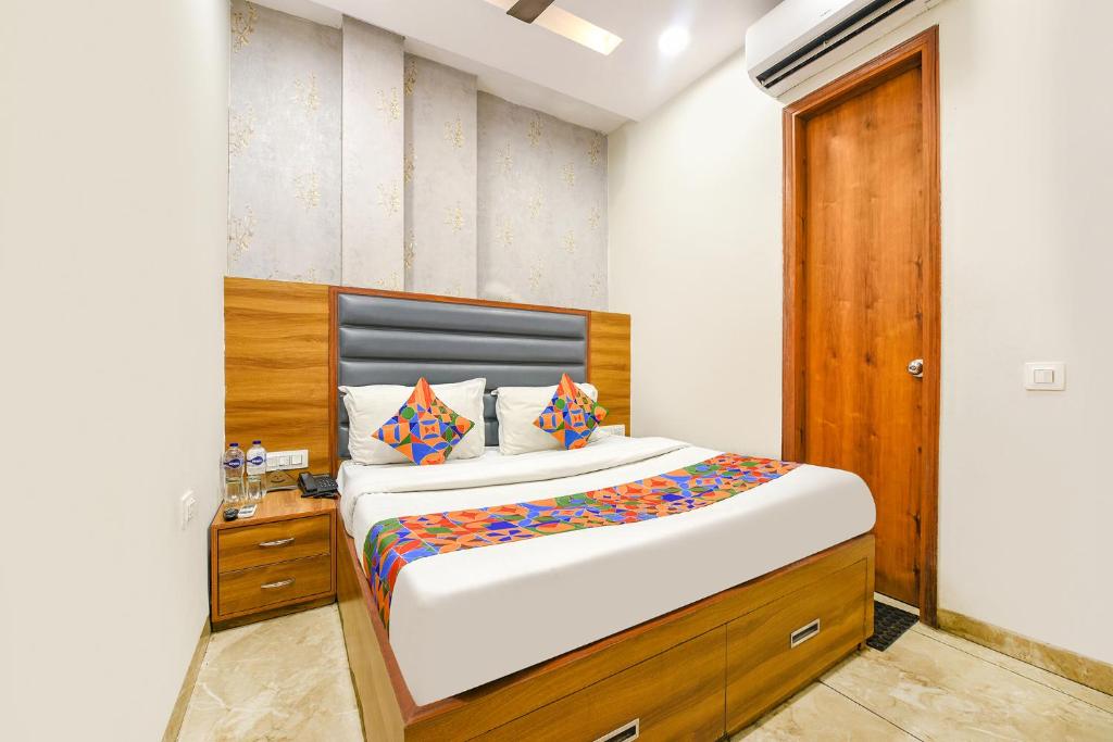a bedroom with a large bed with a wooden headboard at FabExpress Royal MG in Ludhiana