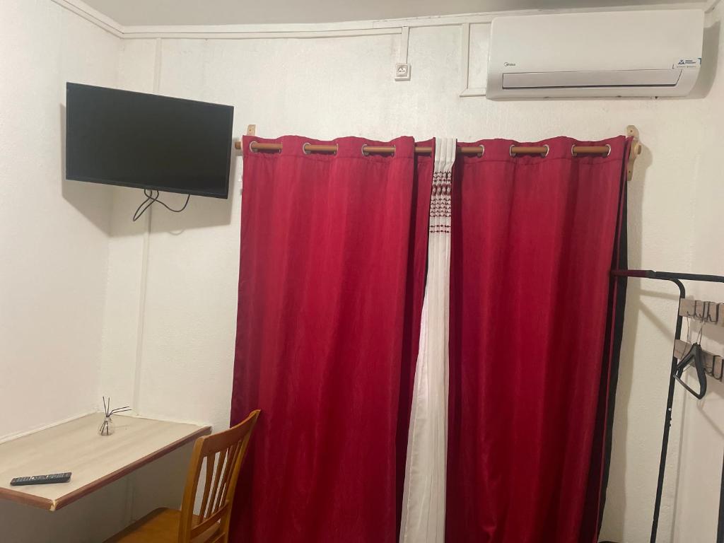 a red curtain in a room with a table and a television at Chambre Mamoudzou in Mamoudzou