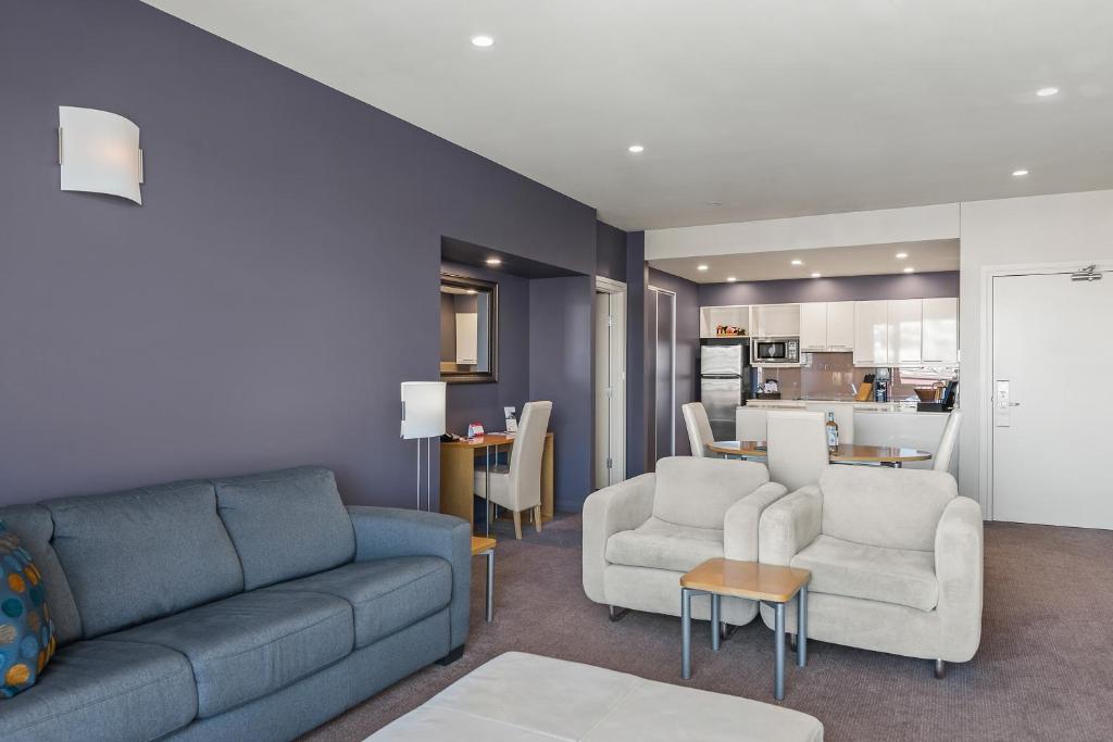 a living room with a couch and chairs and a kitchen at Peppers Seaport Hotel in Launceston