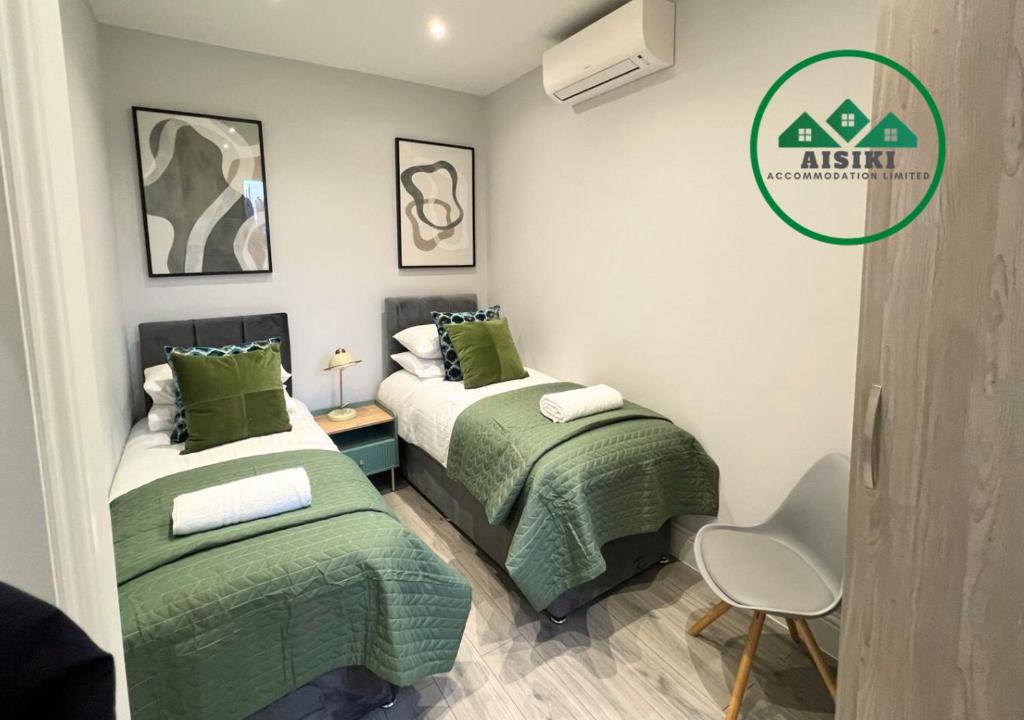 two beds in a small room with green sheets at FW Haute Apartments at Enfield, Pet Friendly Ground Floor 3 Bedrooms and 2 Bathrooms Flat with King or Twin beds with Garden and FREE WIFI and FREE PARKING in London