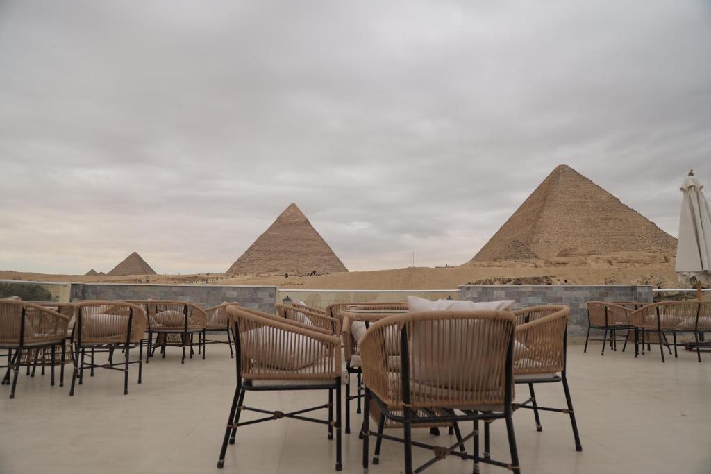 uma fila de cadeiras e mesas em frente às pirâmides em Yamour Pyramids View no Cairo