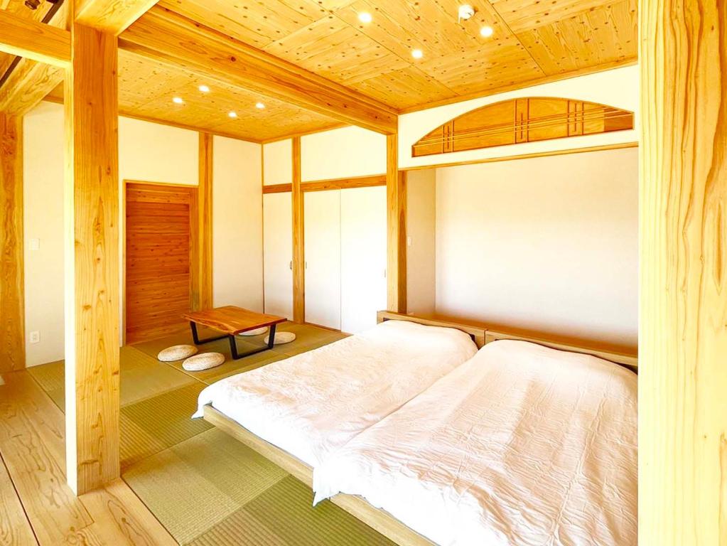 a bedroom with a large bed with a wooden ceiling at 赤瓦の一軒家で伝統とモダンを満喫。ベッド6台、市内観光スポット車で15分以内。12時チェックアウト in Yamazatu