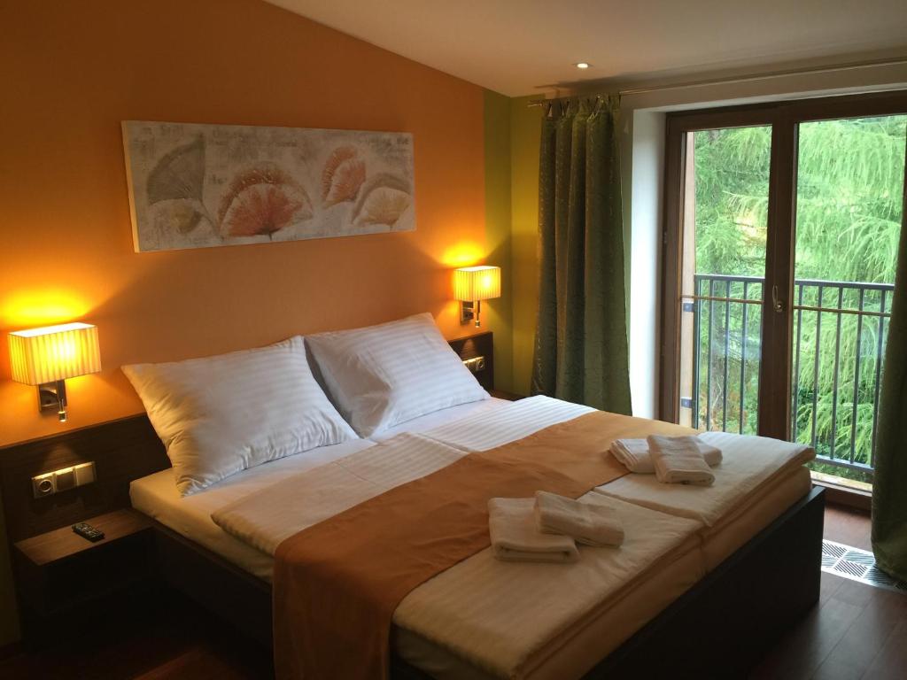 a bedroom with a large bed with two towels on it at Casino & Hotel Admiral Strážný in Strážný