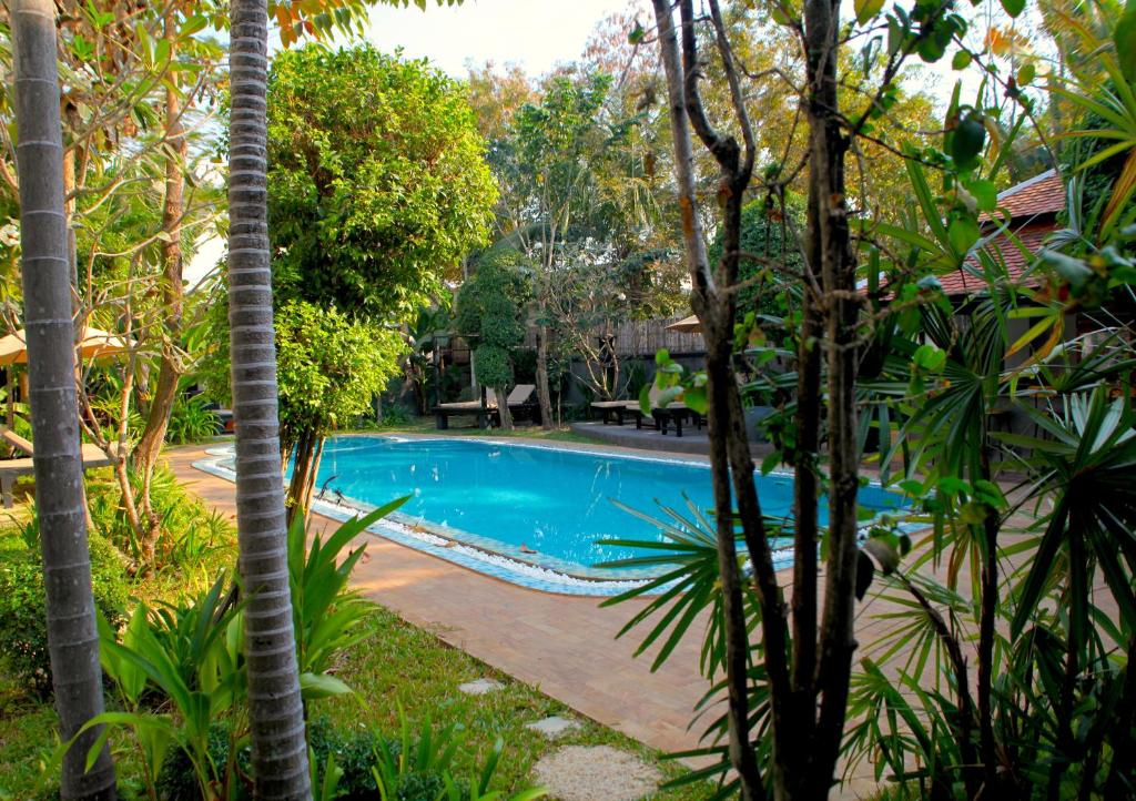 a swimming pool in a garden with palm trees at Prana Hotel in Siem Reap
