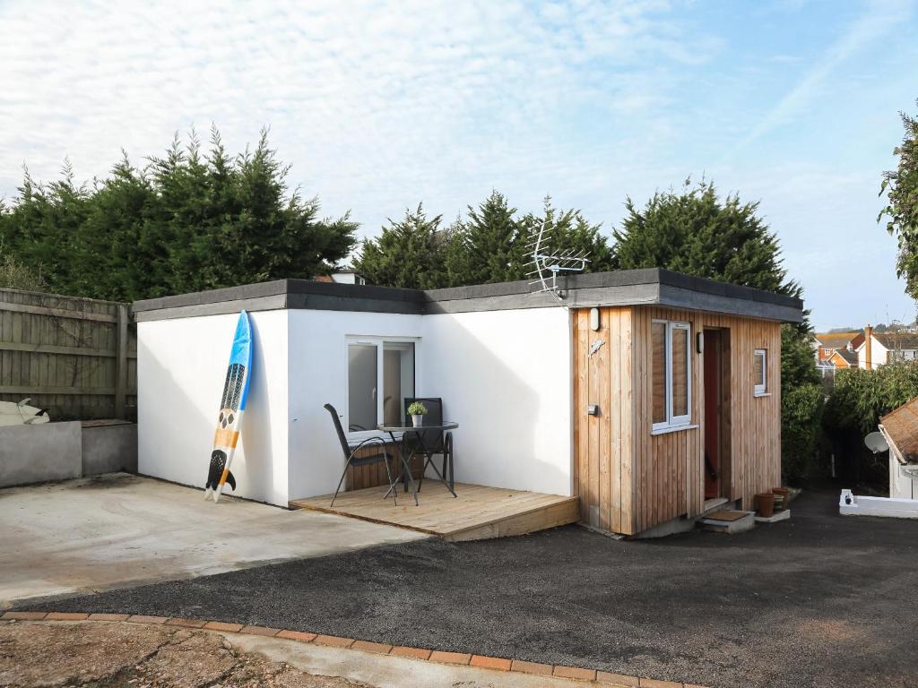 een klein huis met een terras en een surfplank bij Hayfield in Paignton