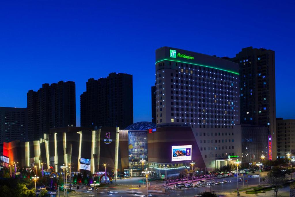a large building with a sign on it at night at Holiday Inn Panjin Aqua City, an IHG Hotel in Panjin