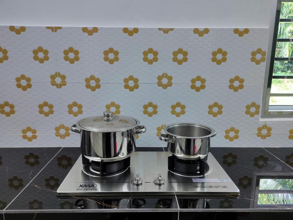 - une cuisine avec 2 casseroles au-dessus d'une cuisinière dans l'établissement Homestay Fayyadh Teluk Intan 3Room2Bath, à Teluk Intan