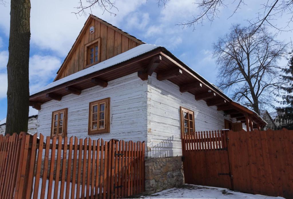 ein kleines weißes Haus mit einem Holzzaun in der Unterkunft Drevenica v Hybe in Hyby