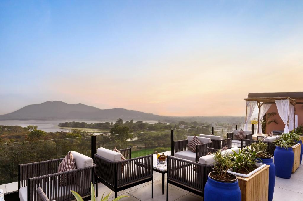 a patio with chairs and a view of the mountains at The Sierra - By The Lake in Udaipur