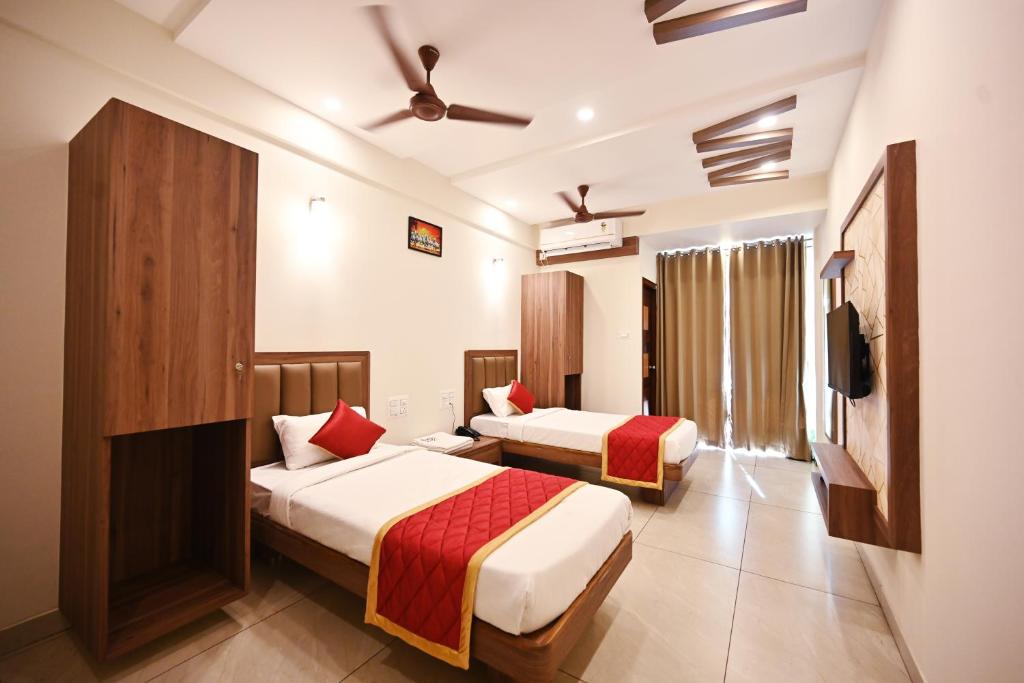 a hotel room with two beds and a tv at Hotel Rays Inn and Pegs Family Restaurant in Dharmastala