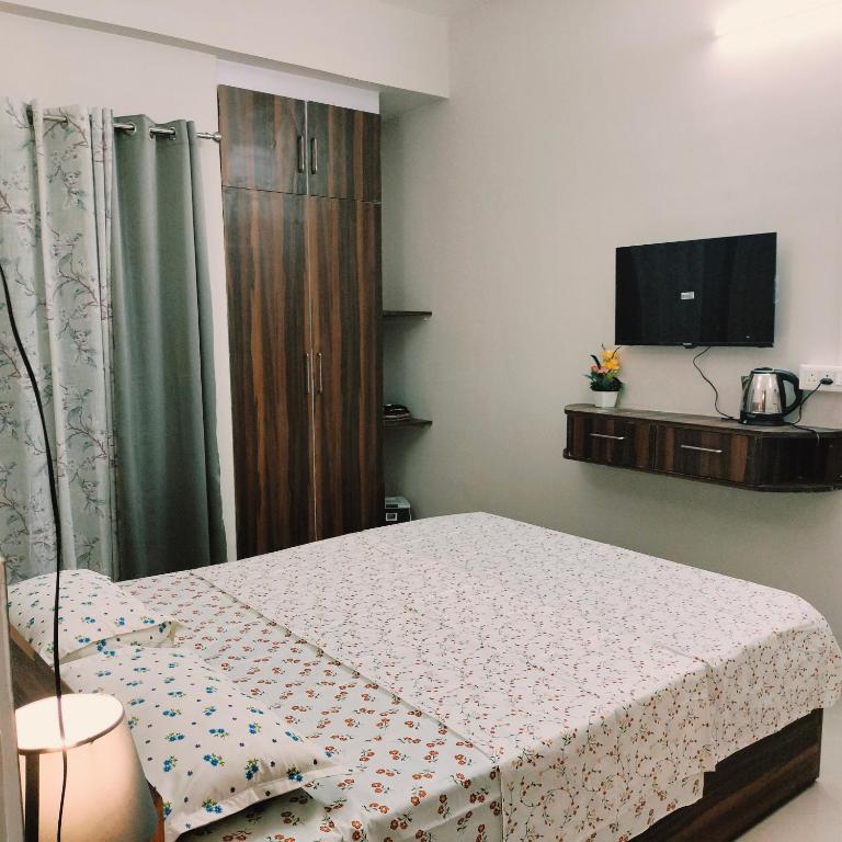 1 dormitorio con 1 cama y TV en la pared en Nester Rooms, en Guwahati