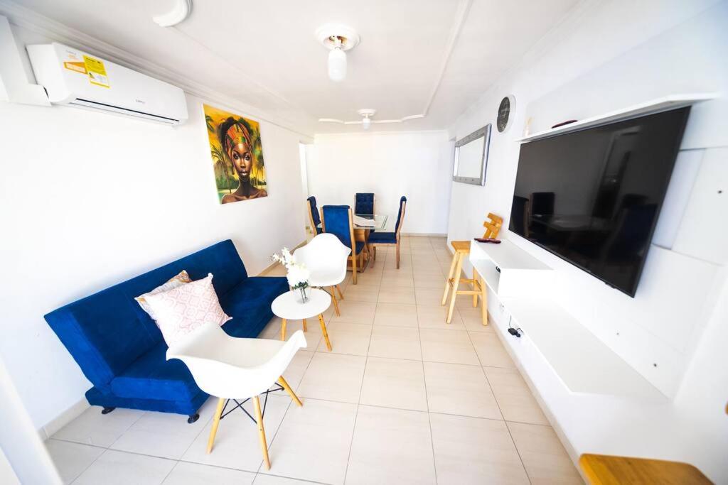 ein Wohnzimmer mit einem blauen Sofa und einem TV in der Unterkunft El Bendecido. Amplio apartamento entero con excelente ubicación y parqueadero privado gratis las 24 Horas. in Cartagena de Indias