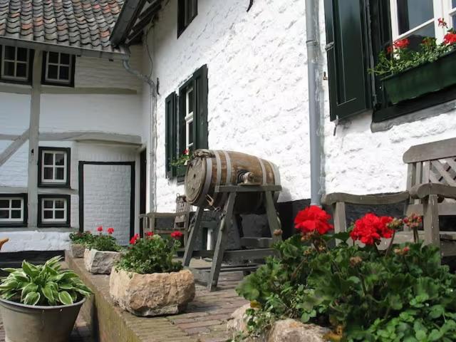 a barrel sitting outside of a house with flowers at Valley view cottage vlakbij Valkenburg in Voerendaal